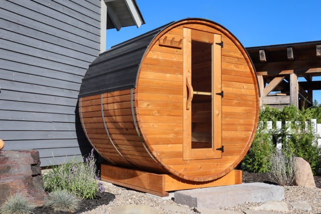 5-ft red cedar barrel outdoor sauna for two people in a landscaped backyard with stone step entry, compact backyard wellness setup
