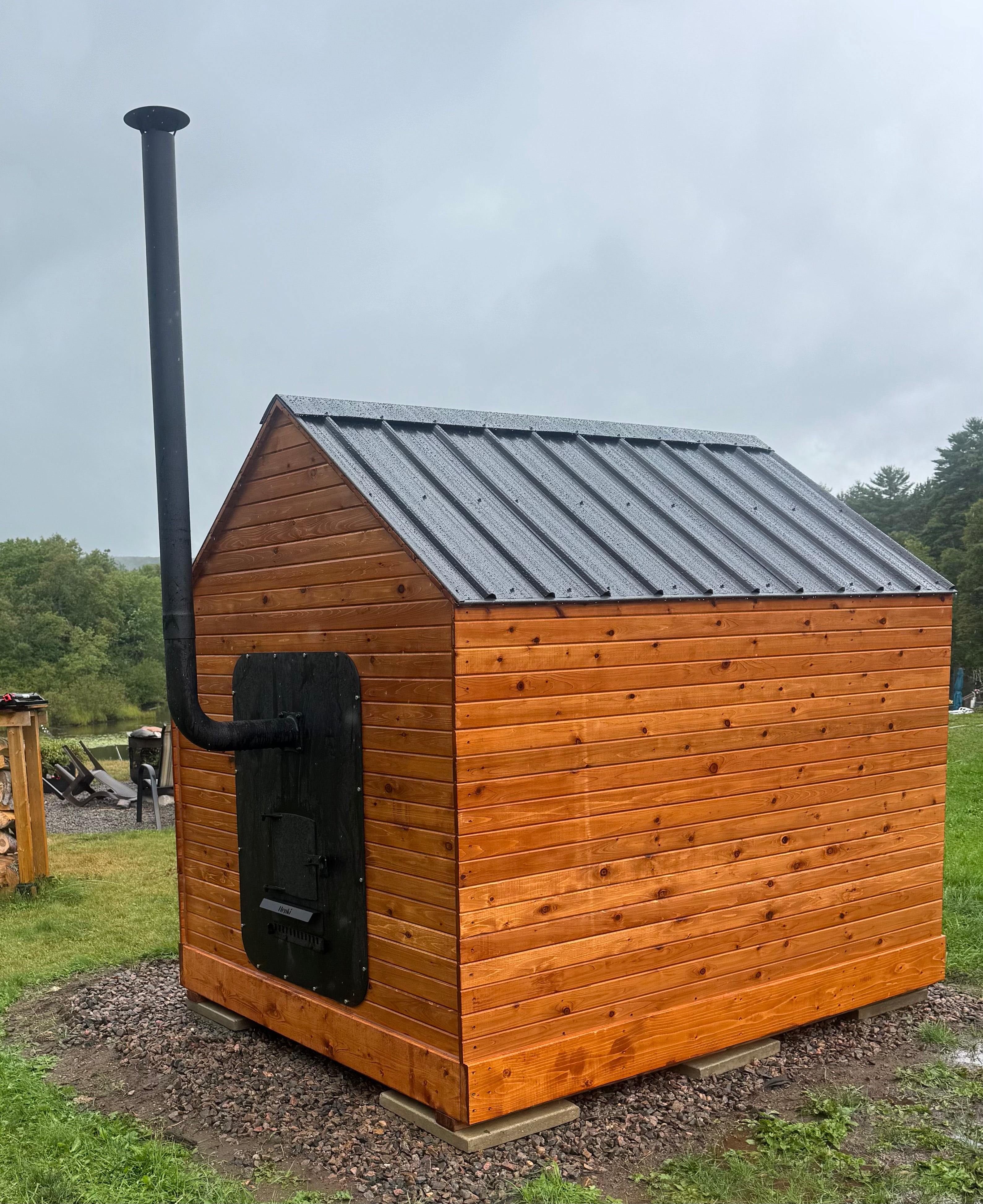 Henki rear loading wood sauna stove installed in outdoor cedar sauna backyard setting