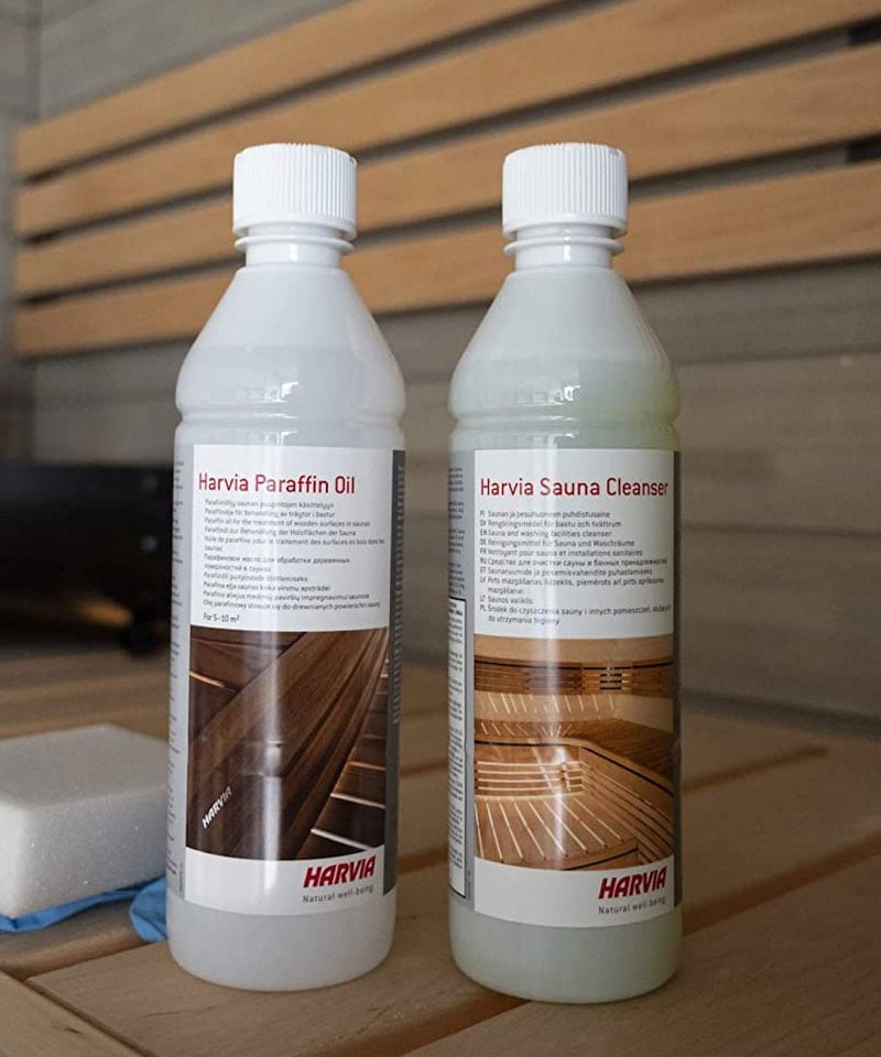 Harvia sauna care product bottles arranged on a cedar sauna bench inside a warm traditional sauna interior