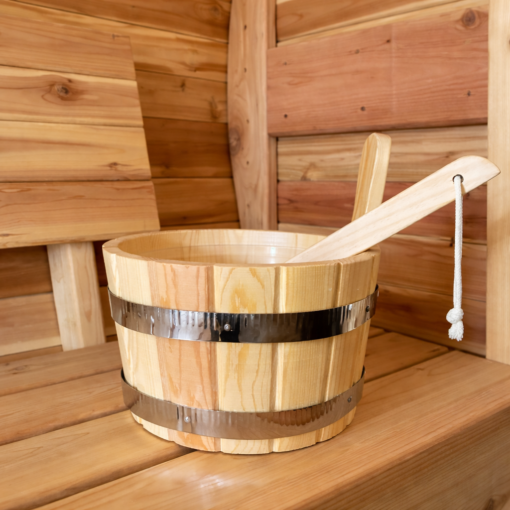 Wood sauna bucket and matching ladle placed on a cedar bench inside a traditional sauna interior