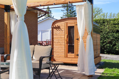 Cube cedar outdoor sauna beside a backyard seating area and gazebo, modern patio wellness setup in a landscaped residential yard